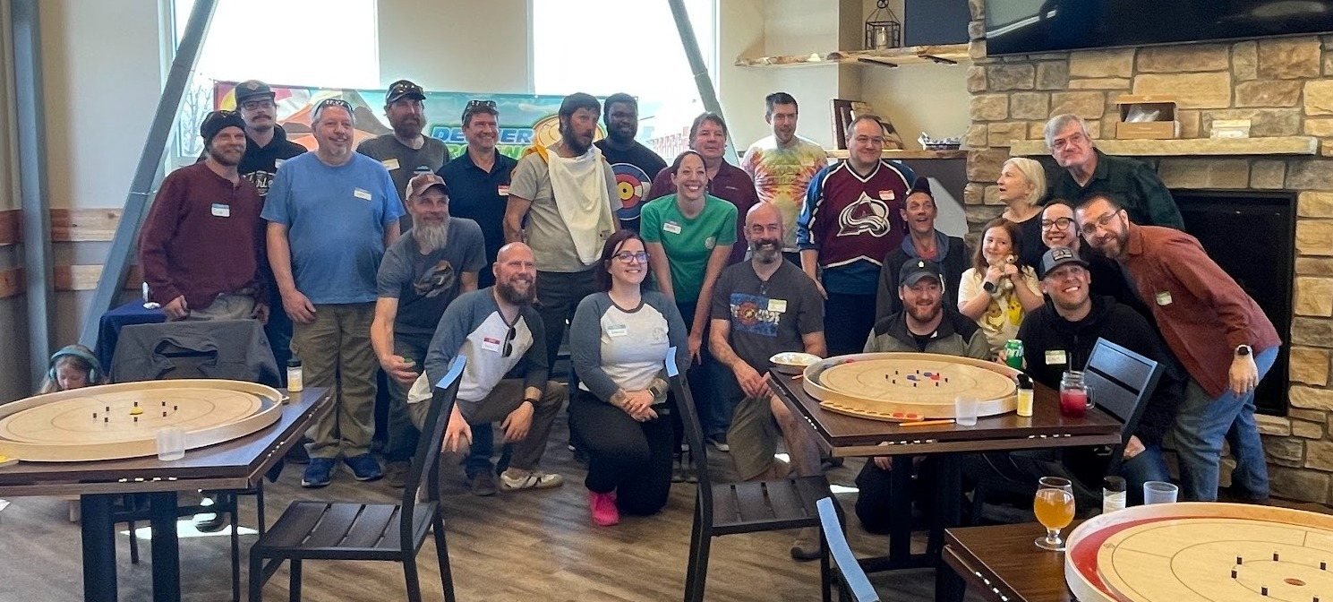 Denver Crokinole Club members gathered around crokinole boards at a club event